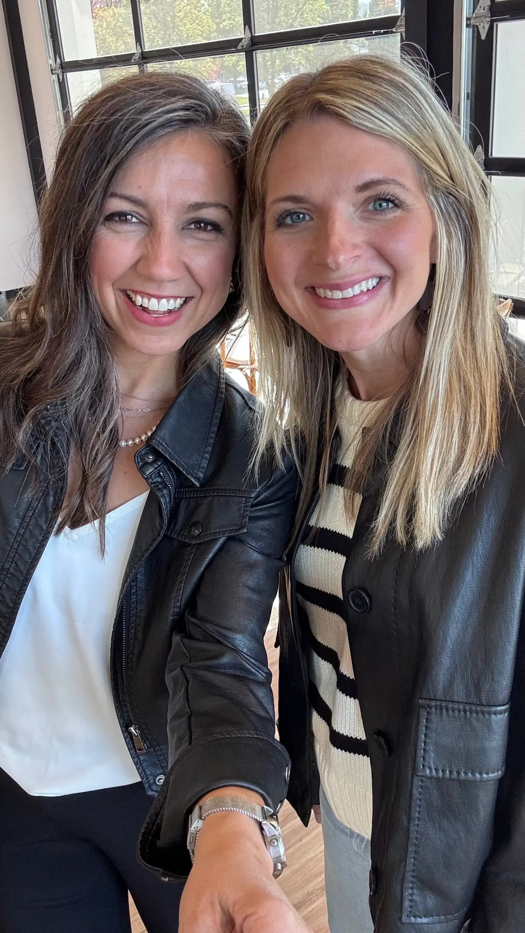 Christine and Angela smiling together in a close selfie inside the showroom